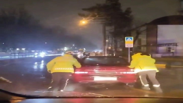 Arızalanan otomobili trafik polisleri yağmurun altında itti